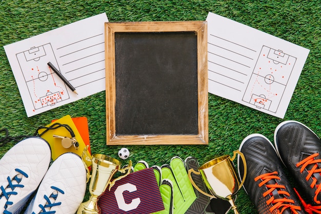 Sports strategy on grass with a blackboard, diagrams, trophies, shoes, and gear; Football Agent theme.