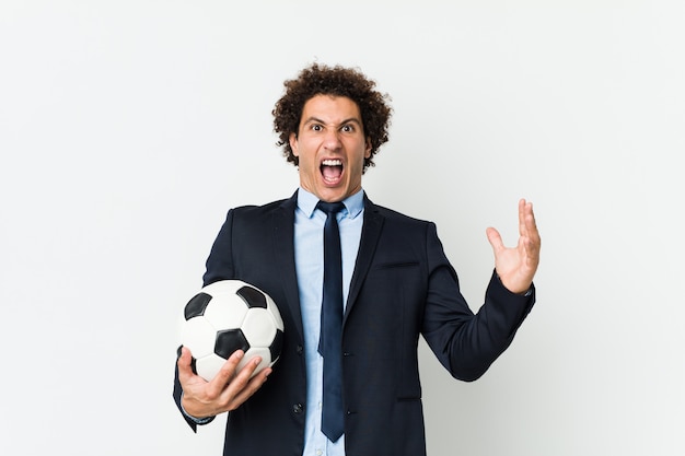 Man in suit holding a soccer ball, expressing excitement. Football Agent concept.